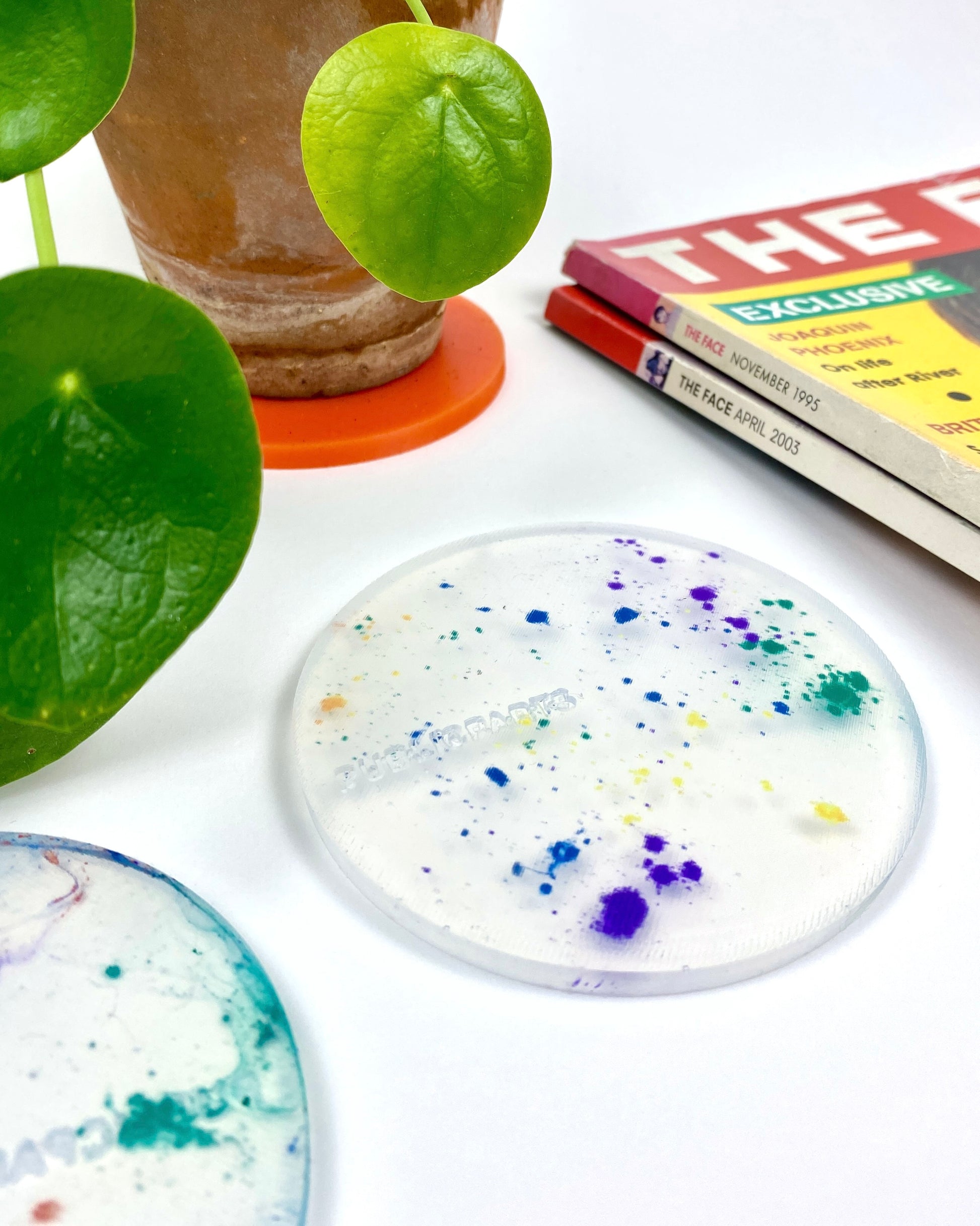 Speckled silicone coaster on a white surface with a plant and magazines in the background