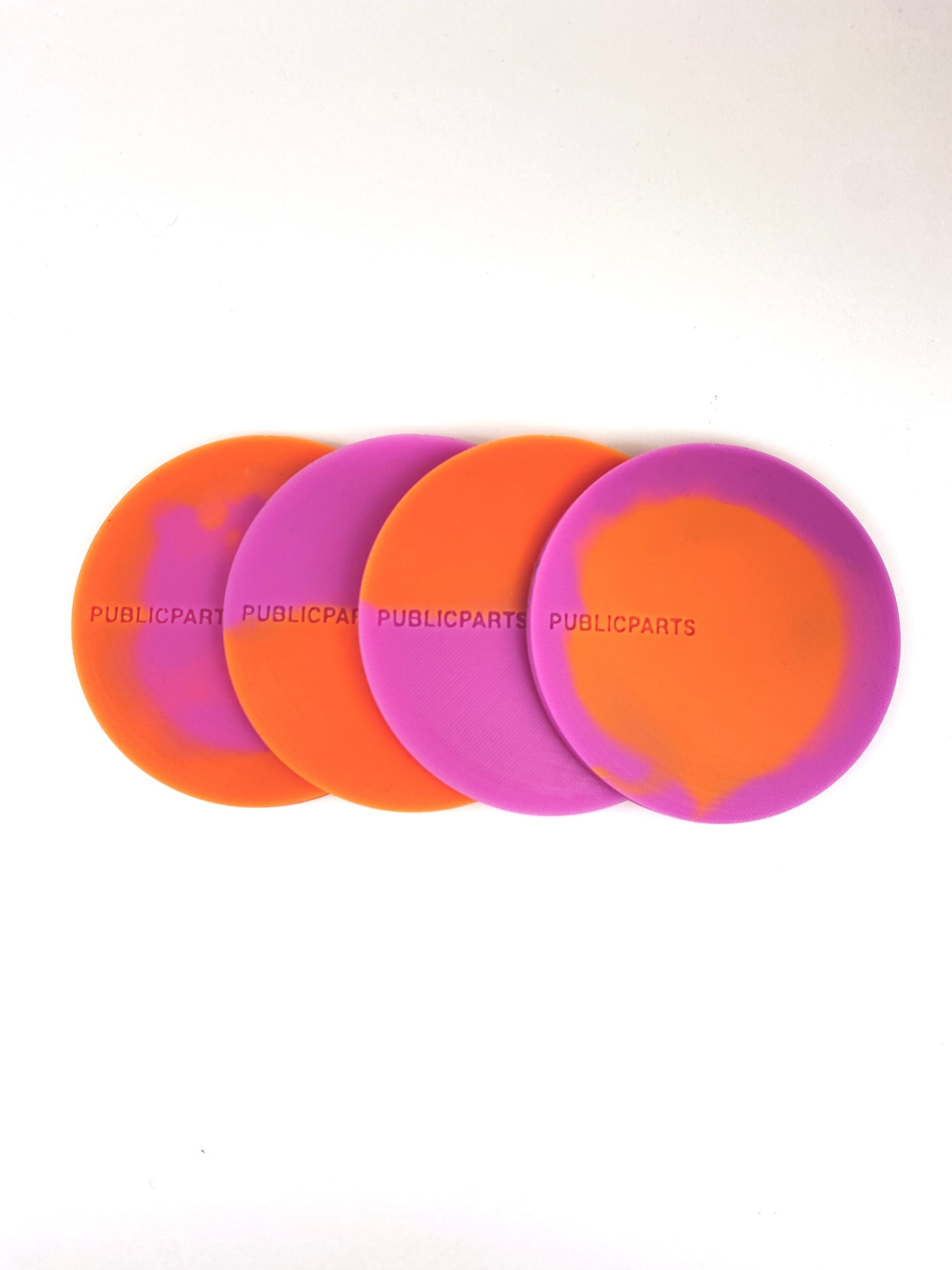 Stacked orange and pink thermochromic silicone coasters showing colour variation.