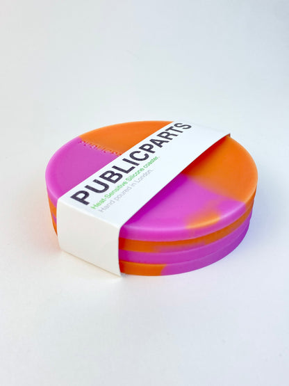 Stack of orange and pink heat-reactive coasters wrapped in PUBLICPARTS branded sleeve.